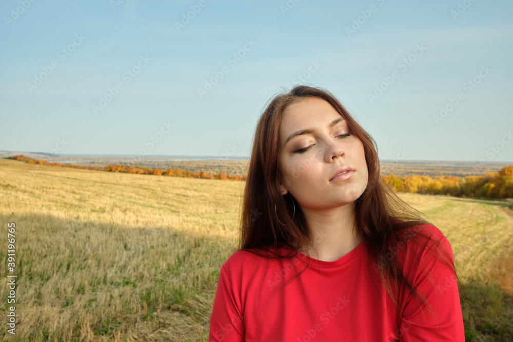 Young beautiful girl in a red dress stands in an autumn field Young beautiful girl in a red dress stands in an autumn field