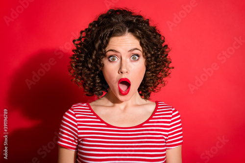 Photo of shocked surprised curly young lady wear casual striped outfit open mouth isolated red color background