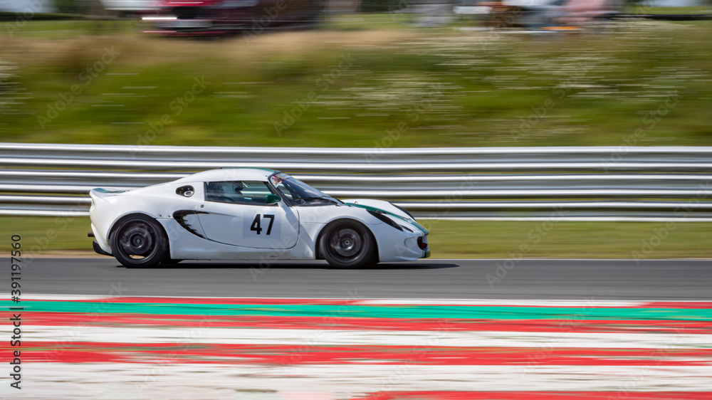 A panning shot of a racing car as it circuits a track.