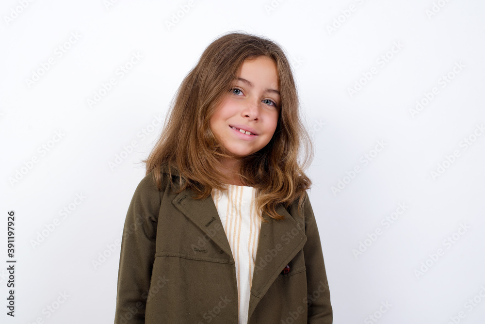Charming Beautiful little girl standing against white background, feeling shy, smiling and looking to the camera. Charming Beautiful little girl standing against white background, feeling shy, smiling and looking to the camera.
