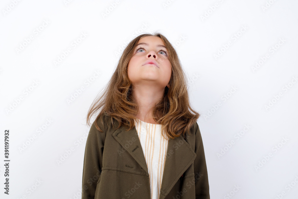 Beautiful little girl standing against white background, looking up as he sees something strange. Beautiful little girl standing against white background, looking up as he sees something strange.