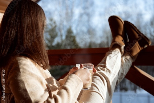 girl sitting with coffee on the veranda and looking at the forest