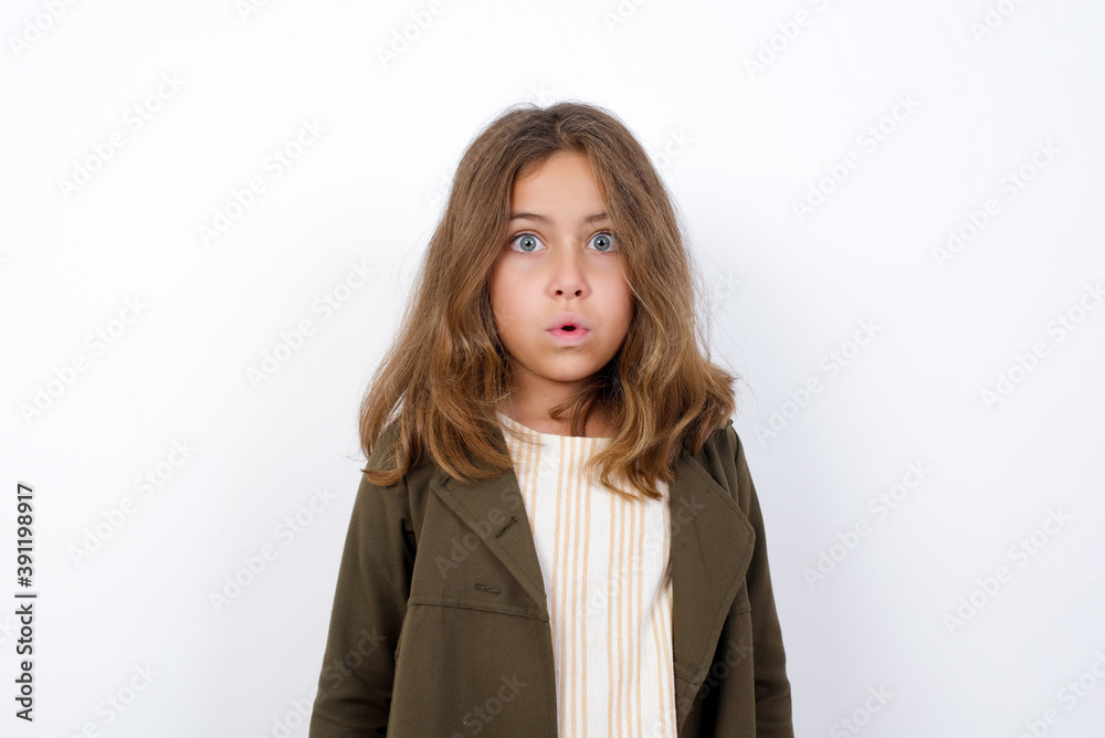 Beautiful little girl standing against white background, expressing disgust, unwillingness, disregard having tensive look frowning face, looking indignant with something. Beautiful little girl standing against white background, expressing disgust, unwillingness, disregard having tensive look frowning face, looking indignant with something.