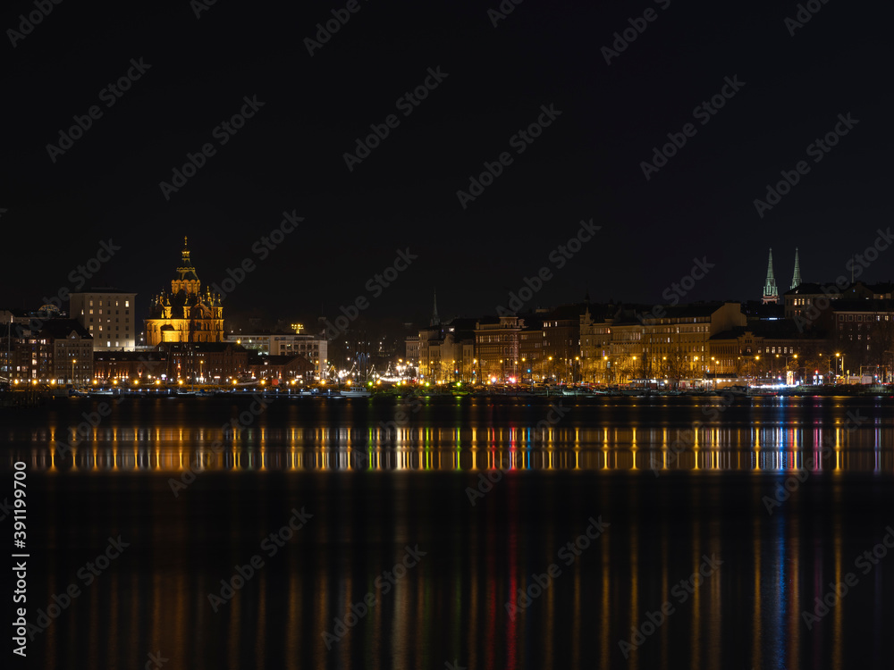 Illuminated Helsinki waterfront with Uspenski Cathedral in the background.