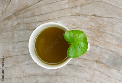tea Centella asiatica, Asiatic Pennywort hot tea in a glass on wood table and got Centella asiatica leave on a glass; photographed tea top view