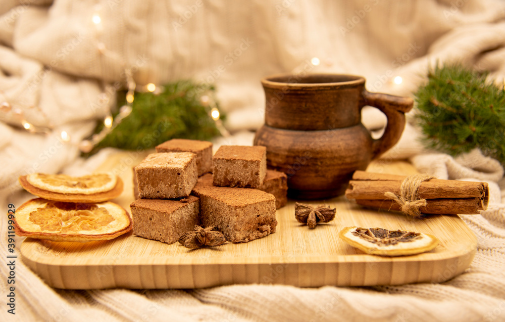 Fototapeta premium A clay mug with a drink and various Goodies are on a wooden tray, standing on a knitted blanket .
