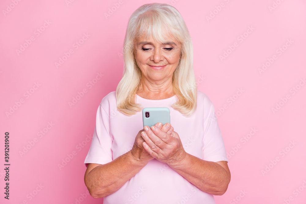 Photo portrait of cute granny using smartphone browsing internet smiling isolated on pastel pink color background Photo portrait of cute granny using smartphone browsing internet smiling isolated on pastel pink color background