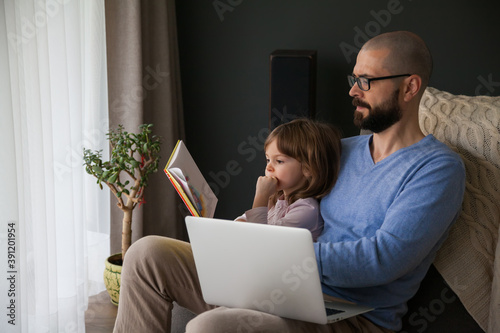 Man trying to work and to read to his daughter at the same time