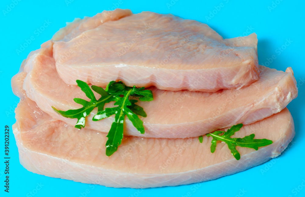fresh turkey steaks with pepper and arugula on blue background fresh turkey steaks with pepper and arugula on blue background