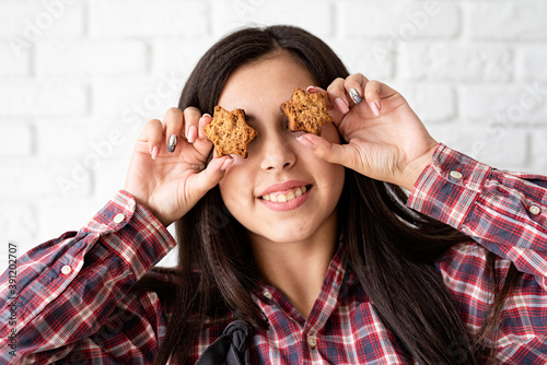 Happy woman in apron holding star shaped cookies in front of her eyes