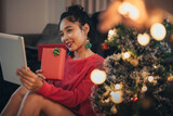 Woman making video call on social network and giving Christmas gift on Christmas day. Happy girl celebrating Christmas from social network.