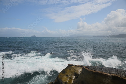 The waves crashed against the rocks. Overlooking the Keelung Islet under the blue sky and white clouds. photo