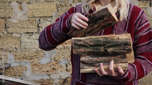 Woman hold firewood. Horizontal concept with firewood in the hand of a girl, takes care of the firewood in the house to light the fireplace. Rustic countryside background warmth and firewood