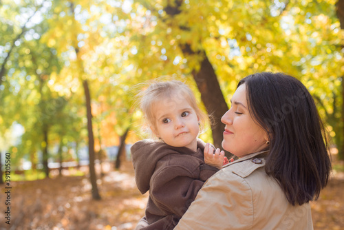 A young mother and little daughter are walking and laughing in the autumn park. Family. Autumn mood