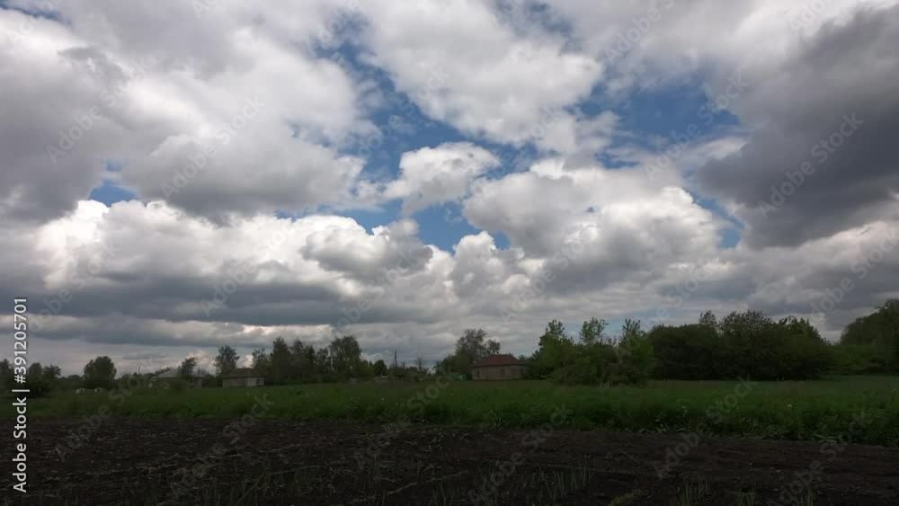 White cumulus clouds over an old village on a summer evening. Landscape, time-lapse. White cumulus clouds over an old village on a summer evening. Landscape, time-lapse.