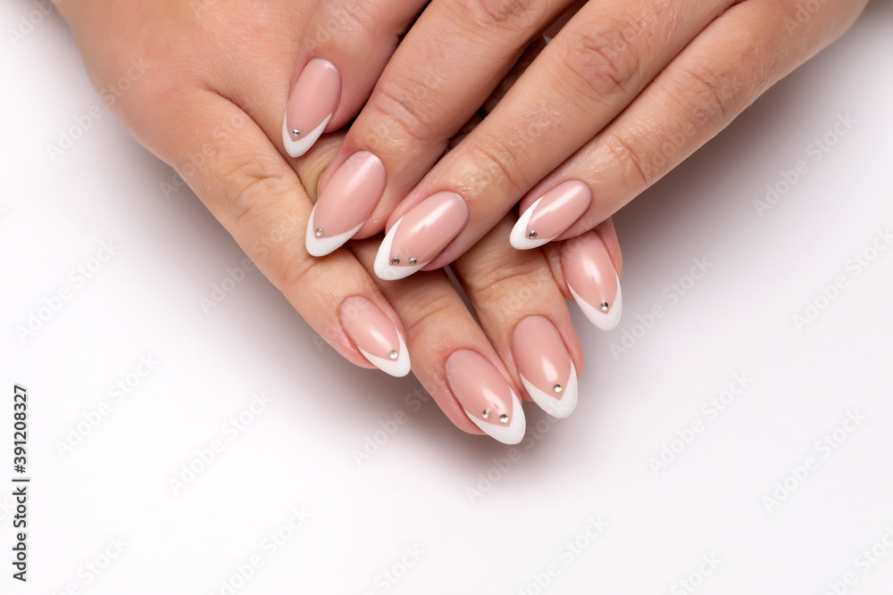 Gel manicure with crystals, stones on all nails. French white sharp manicure on long sharp nails close-up on a white background. Gel manicure with crystals, stones on all nails. French white sharp manicure on long sharp nails close-up on a white background.