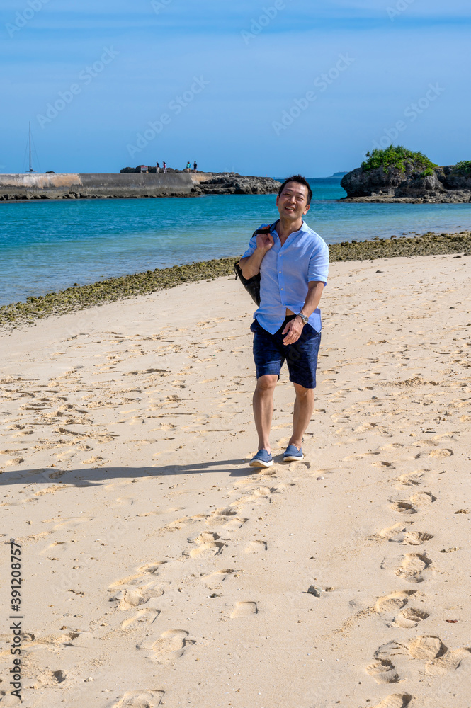 A Japanese man walks on a beach in Irabu Island, Miyakojima, Okinawa, Japan A Japanese man walks on a beach in Irabu Island, Miyakojima, Okinawa, Japan