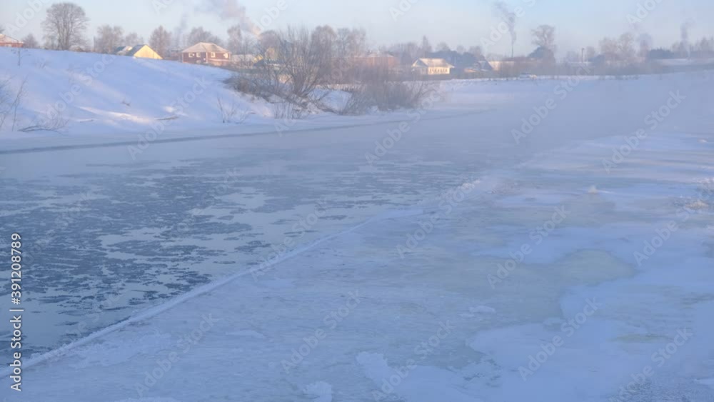 Winter snow river landscape. Rural scene. Ice floats on the river. Steam escaping over the frozen river in winter. 4K footage Winter snow river landscape. Rural scene. Ice floats on the river. Steam escaping over the frozen river in winter. 4K footage
