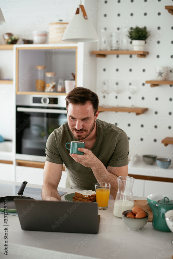 Young man eating breakfast and reading the news online. Handsome man enjoying at home. Young man eating breakfast and reading the news online. Handsome man enjoying at home.