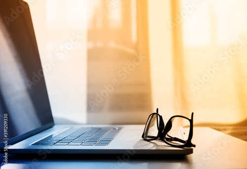 open laptop on which lie reading glasses in black frames. selective focus . High quality photo