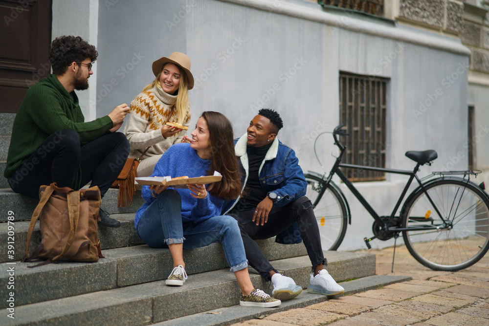 Fototapeta premium Group of young people outdoors in town, eating pizza. Coronavirus concept.