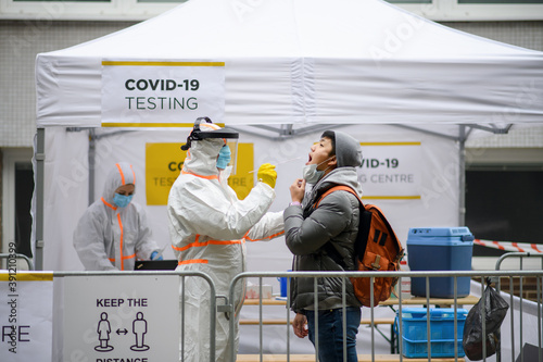 Young man in covid-19 testing center outdoors on street, coronavirus and taking swab concept. photo