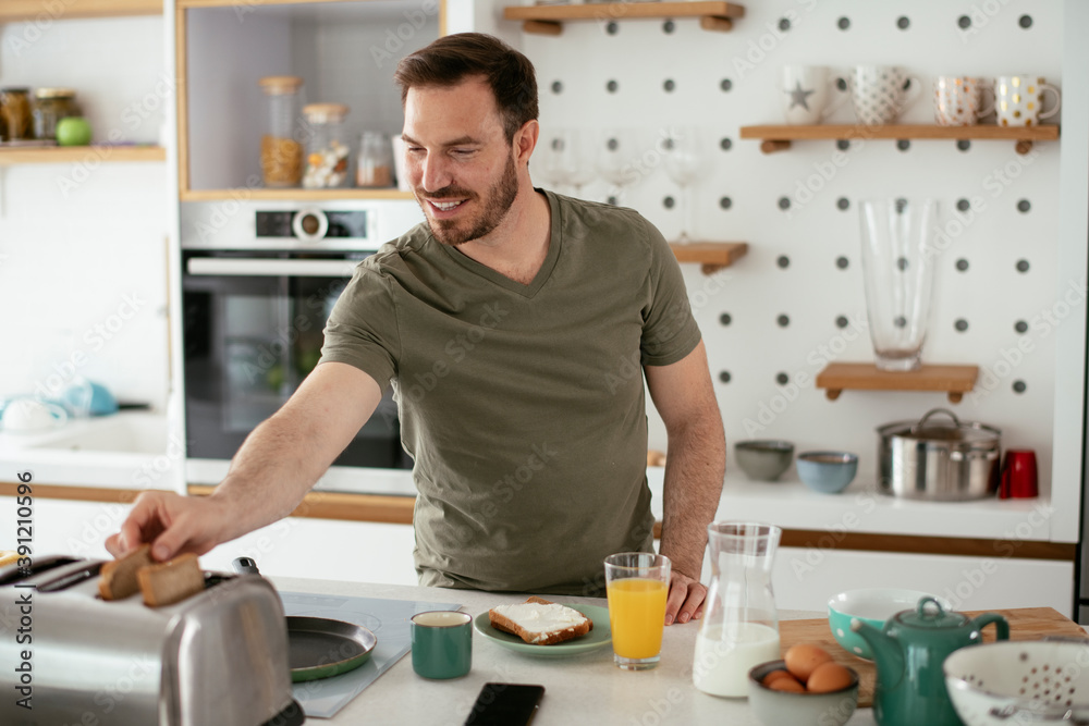 Handsome man preparing breakfast at home. Young man enjoying in morning. Handsome man preparing breakfast at home. Young man enjoying in morning.