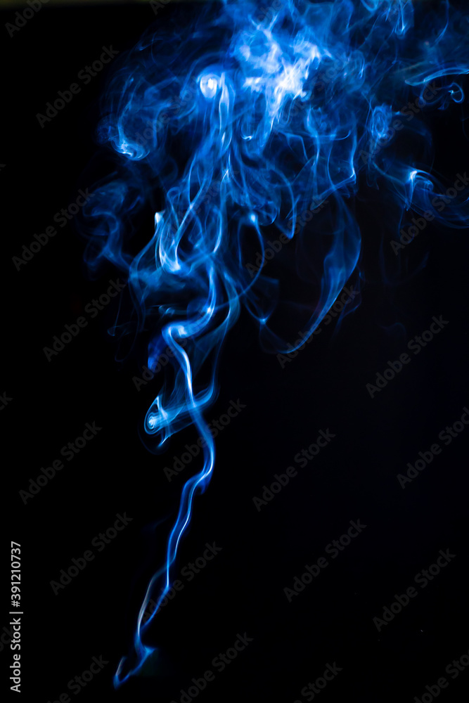 Trickle of vape smoke isolated on black background. Swirls of smoke with blue light, vertical photography for design Trickle of vape smoke isolated on black background. Swirls of smoke with blue light, vertical photography for design