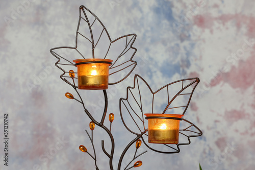 Canvas Print Autumn composition with ornate candleholder with maple leaves design and lit can