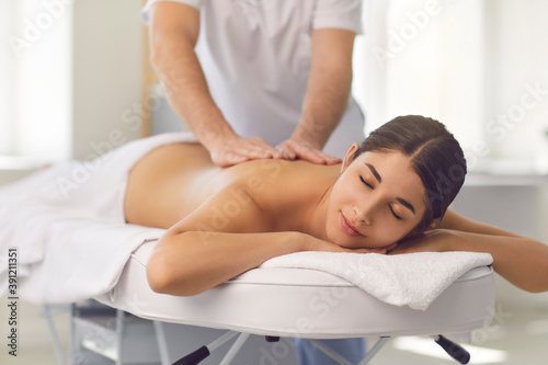 Young male osteopath doing professional back massage for woman in medical center.