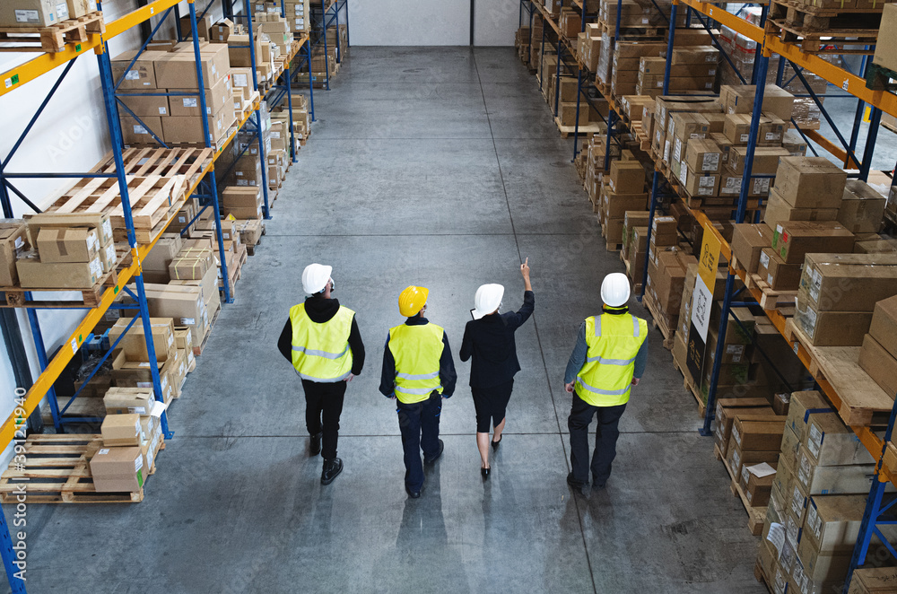 Top rear view of group of workers with manager working indoors in warehouse, coronavirus concept. Top rear view of group of workers with manager working indoors in warehouse, coronavirus concept.
