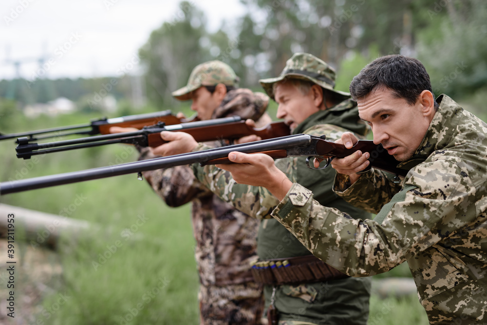 Hunters in Forest Aiming with Rifles Carefully.
