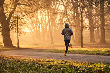 Man running in park at autumn, fall during early morning. Healthy lifestyle concept.