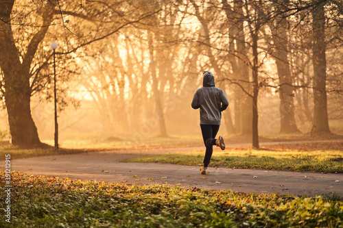 Man running in park at autumn, fall during early morning. Healthy lifestyle concept.