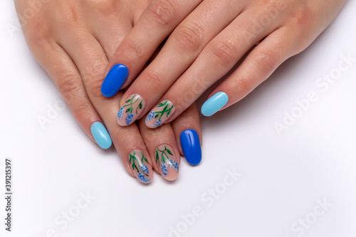 Dark blue, light blue manicure with painted summer flowers on oval long nails close-up on a white background.