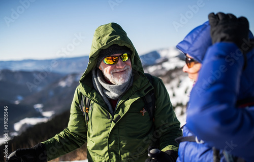 Senior couple hikers talking in snow-covered winter nature.