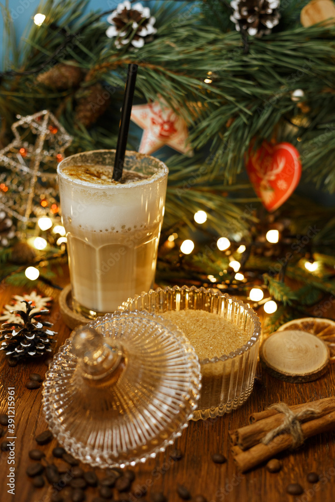 Aromatic cappuccino with foam and straw placed on wooden table in cafe decorated for Christmas holiday Aromatic cappuccino with foam and straw placed on wooden table in cafe decorated for Christmas holiday