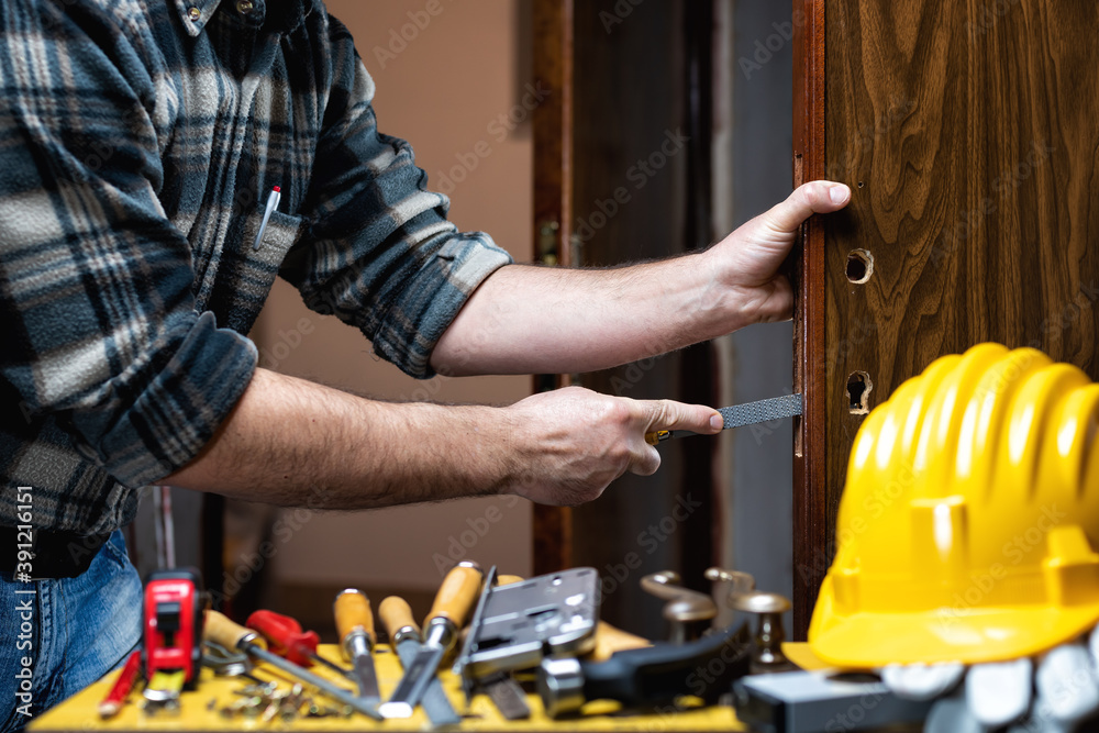 Carpenter at work repairs and installs the door lock. Carpentry. Carpenter at work repairs and installs the door lock. Carpentry.