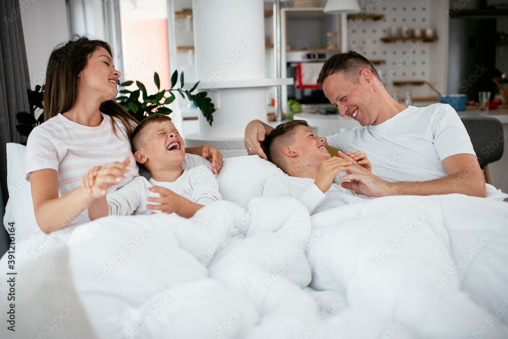 Young family enjoying in bed. Happy parents with sons relaxing in bed... Young family enjoying in bed. Happy parents with sons relaxing in bed...
