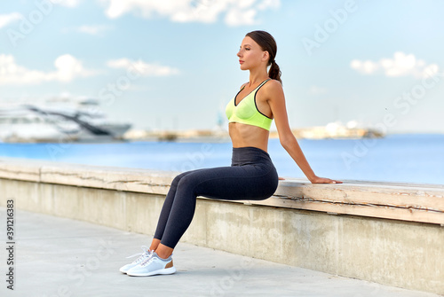 fitness, sport and healthy lifestyle concept - young woman exercising on sea promenade