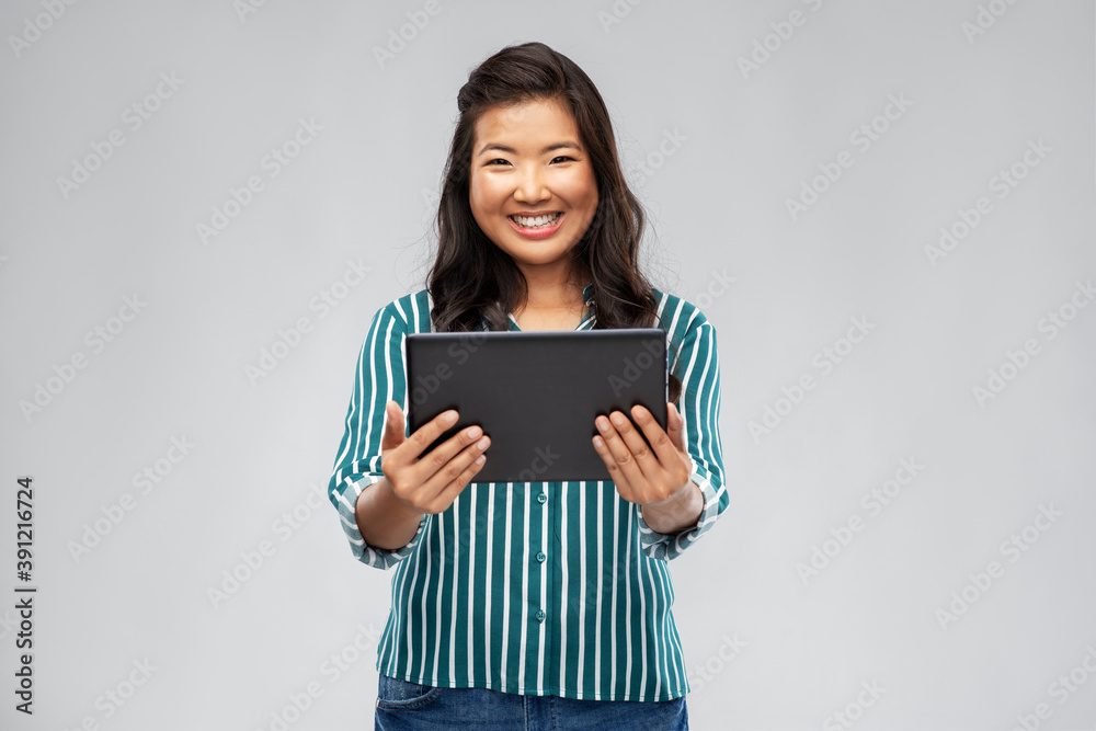 technology and people concept - happy asian woman using tablet computer over grey background technology and people concept - happy asian woman using tablet computer over grey background
