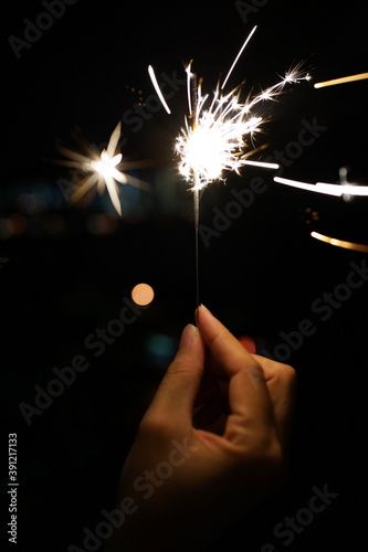 Cropped Hand Holding Sparkler At Night