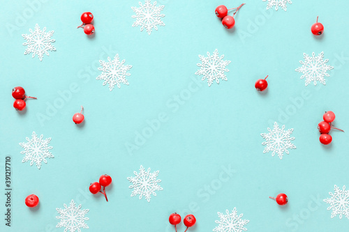 Christmas sale. Red berry, white snowflakes in shape frame on pastel blue background for greeting card. Xmas backdrop with space for text.