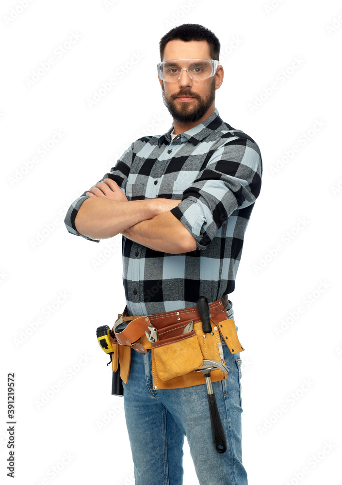 profession, construction and building - happy smiling male worker or builder in goggles with crossed arms over white background