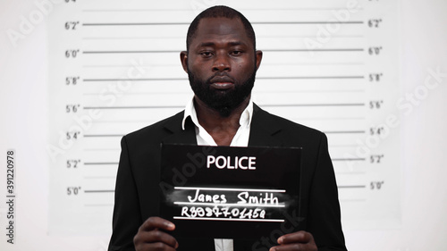 Mugshot of criminal afro-american businessman at police station photo