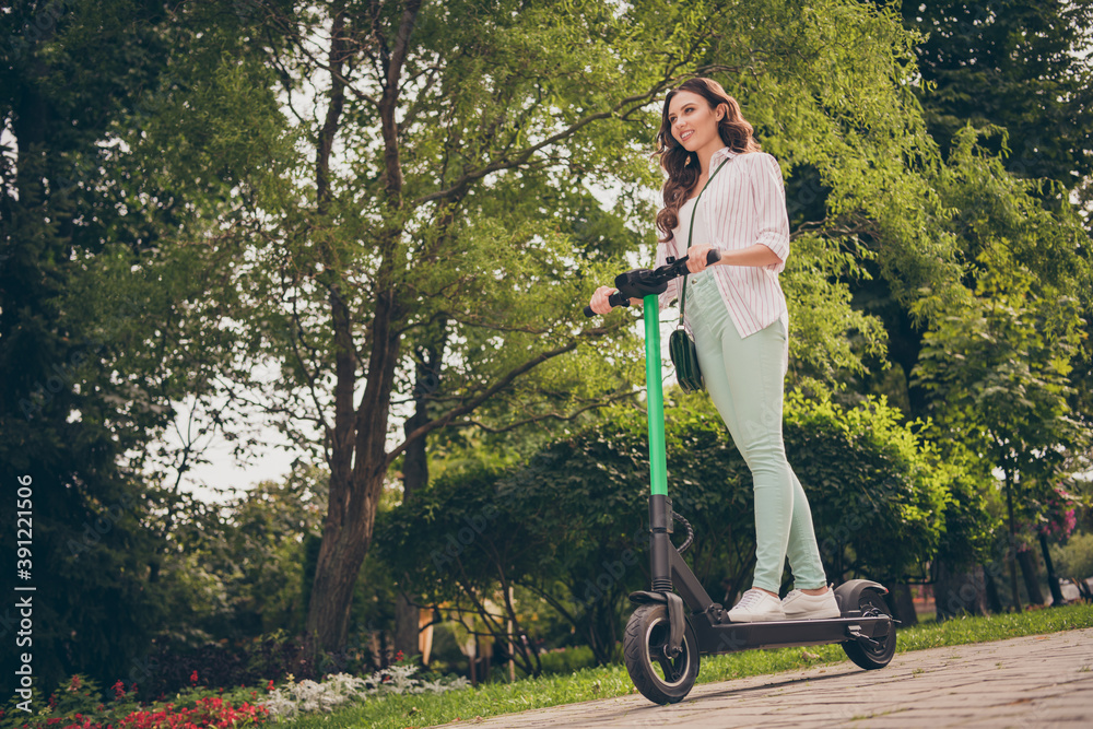 Low angle view full body photo of pretty happy positive girl wear casual outfit ride electric scooter in park fun enjoy Low angle view full body photo of pretty happy positive girl wear casual outfit ride electric scooter in park fun enjoy