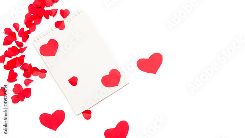 Valentine day composition: Notebook with the strewn with hearts on white background with copy-space. Top View.