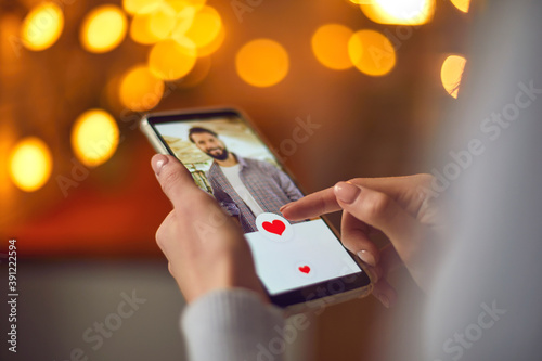 Closeup of woman looking at young man's profile photo on dating app and pressing like button photo