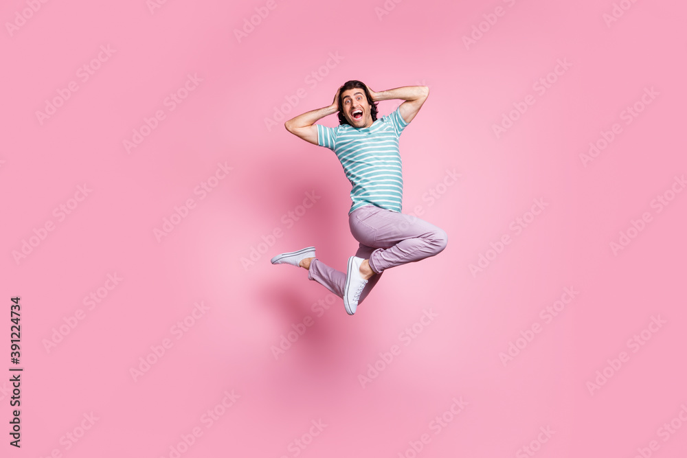 Full length photo of impressed young guy dressed casual clothes jumping arms head isolated color background Full length photo of impressed young guy dressed casual clothes jumping arms head isolated color background