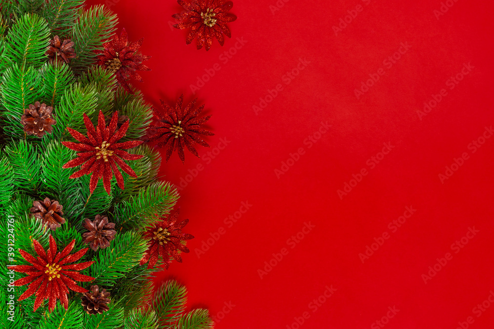 postcard from the branches of a Christmas tree with pine cones and shiny red flowers on a saturated background, copy space.